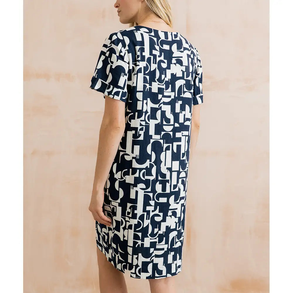 Woman wearing a navy and white patterned dress against a beige background