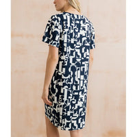 Woman wearing a navy and white patterned dress against a beige background