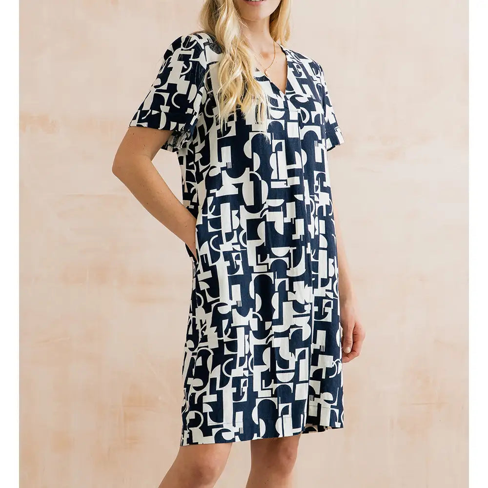 Woman wearing a navy and white patterned dress against a beige background