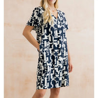 Woman wearing a navy and white patterned dress against a beige background