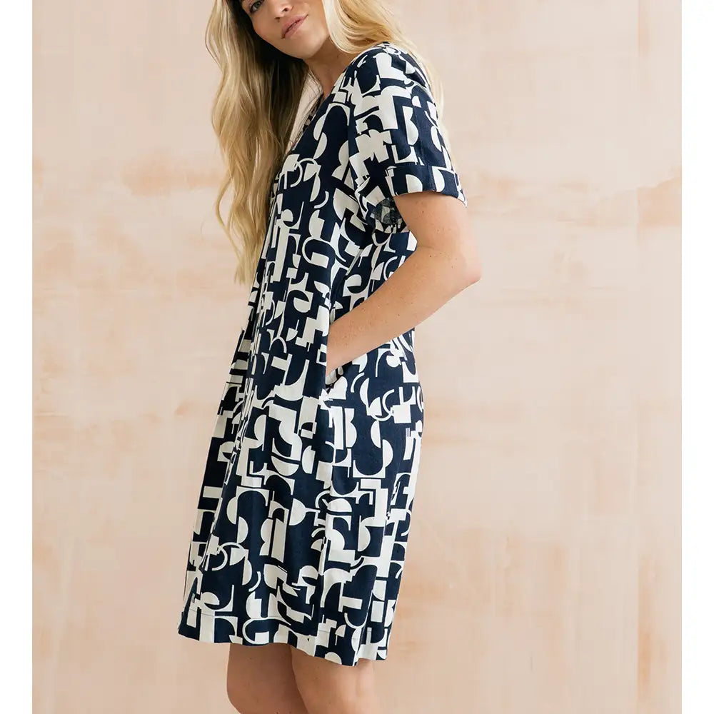 Woman wearing a navy and white patterned dress against a beige background