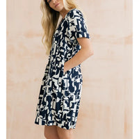 Woman wearing a navy and white patterned dress against a beige background