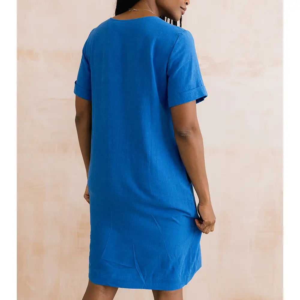 Person wearing a blue dress against a beige background