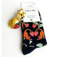Pair of socks with fox and strawberry design on a white background, featuring a small plush toy attached.