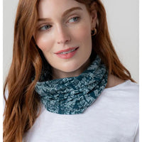 Woman wearing a teal patterned scarf against a white background
