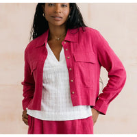 Woman wearing a pink jacket over a white top on a beige background