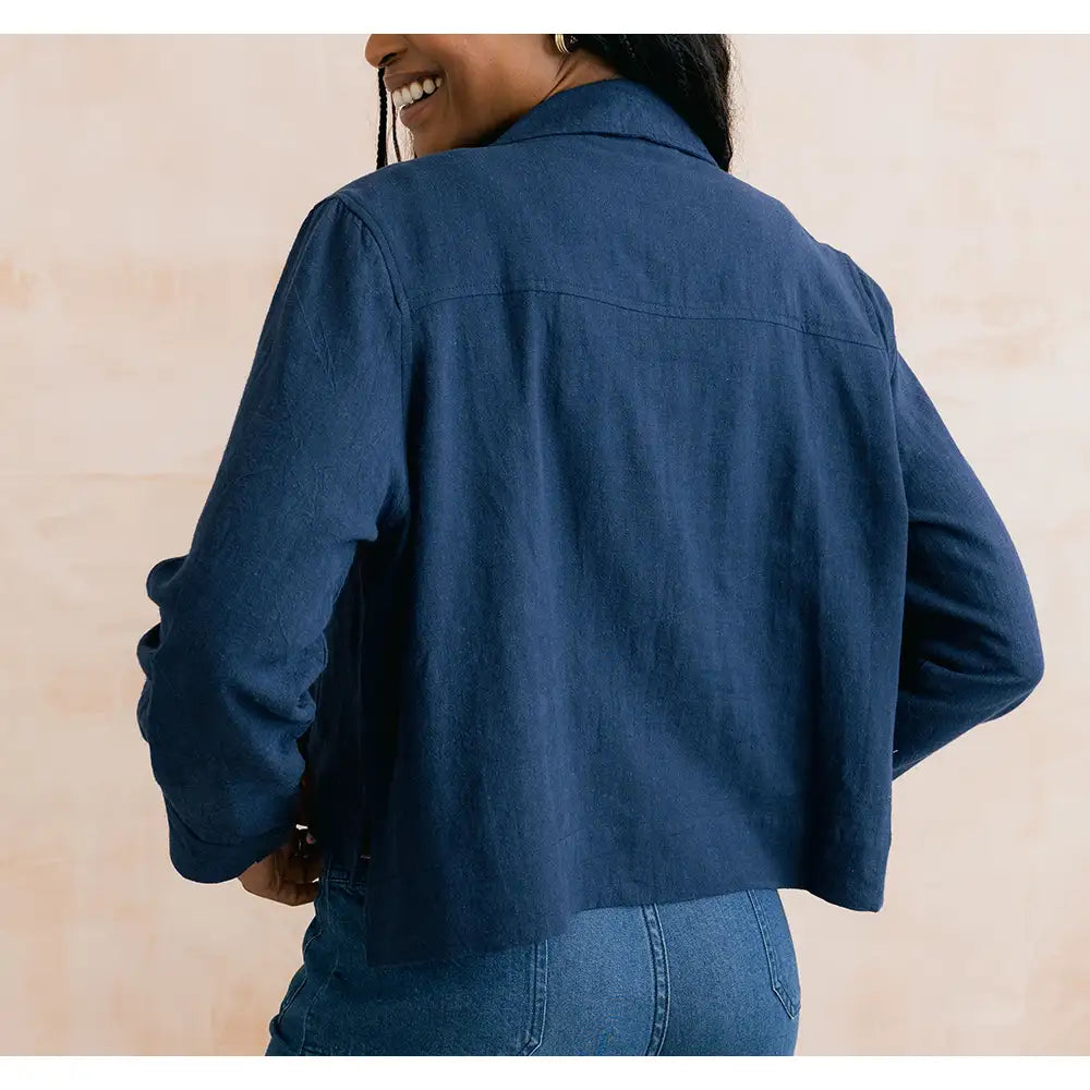 Person wearing a blue denim jacket on a beige background