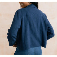 Person wearing a blue denim jacket on a beige background