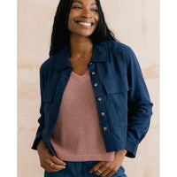 Woman wearing a navy blue jacket over a pink top on a beige background