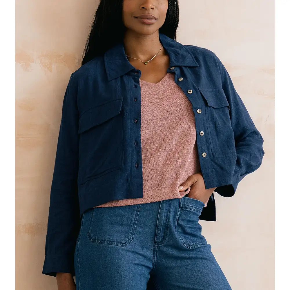 Woman wearing a navy blue jacket over a pink top on a beige background