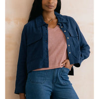 Woman wearing a navy blue jacket over a pink top on a beige background