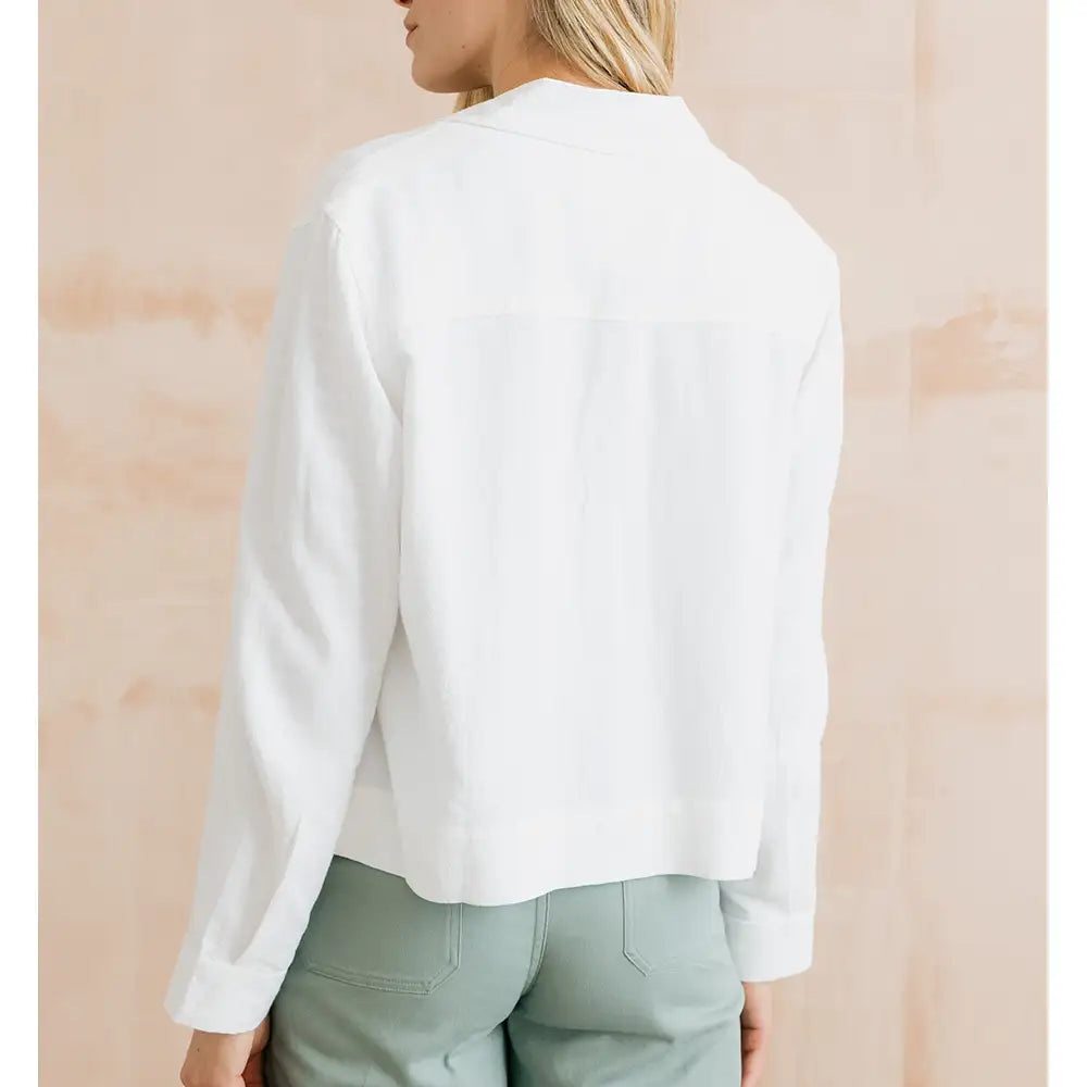 Person wearing a white blouse with a neutral background