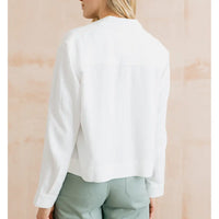 Person wearing a white blouse with a neutral background