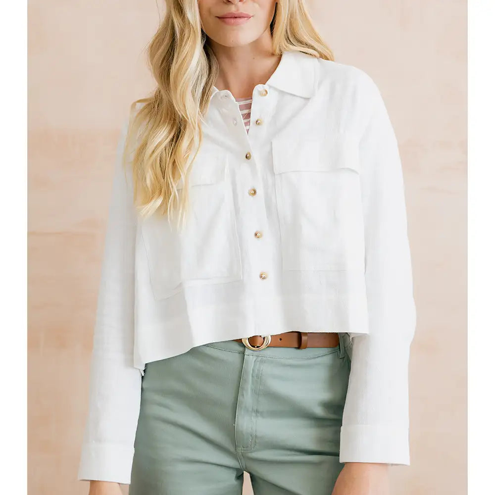 Person wearing a white button-up shirt and green pants against a beige background