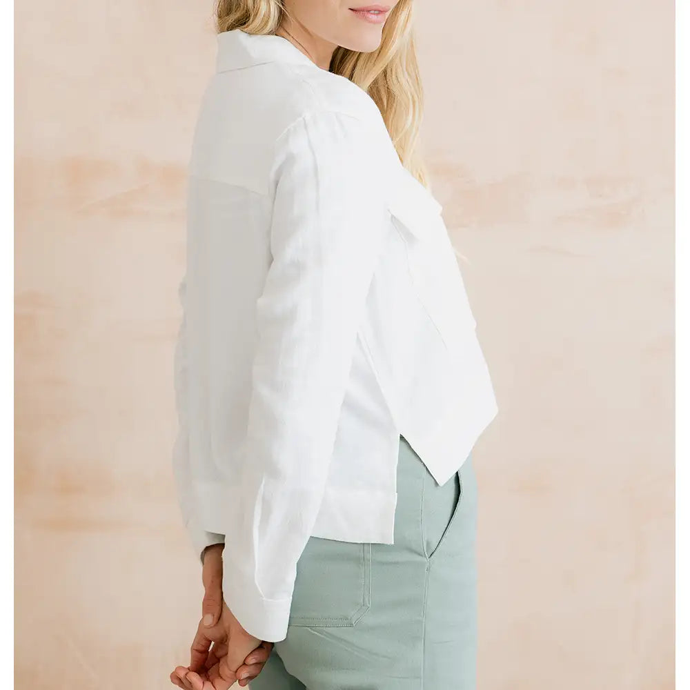 Person wearing a white blouse with long sleeves against a beige background