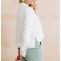 Person wearing a white blouse with long sleeves against a beige background