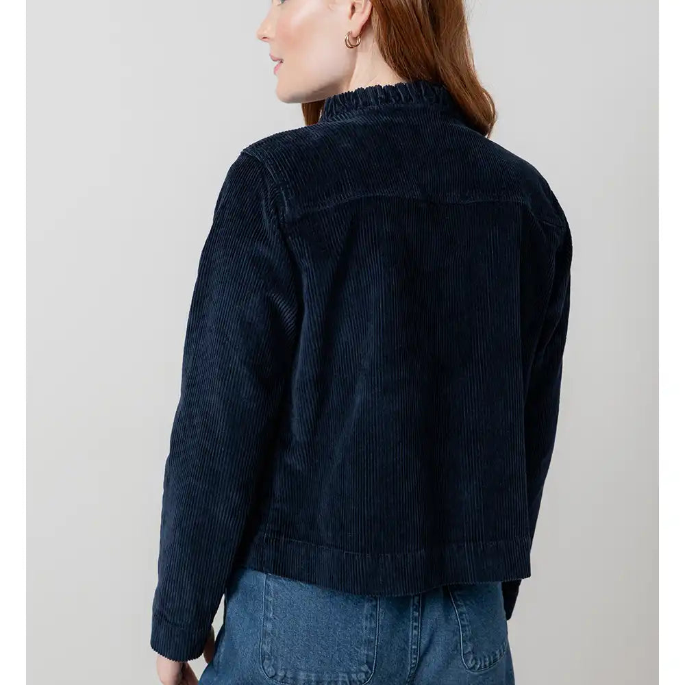 Person wearing a dark blue corduroy jacket on a plain background