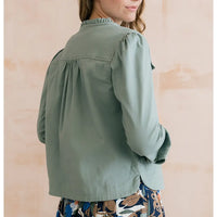 Person wearing a green jacket with a neutral background