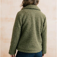 A person shown from the back wearing a textured, boucle-style olive green fleece jacket against a light beige background.