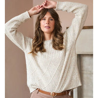 Woman wearing a cream knitted sweater with a neutral background