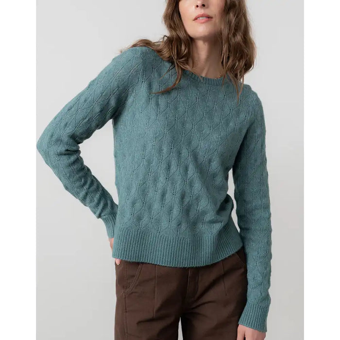 Woman wearing a teal sweater against a plain background