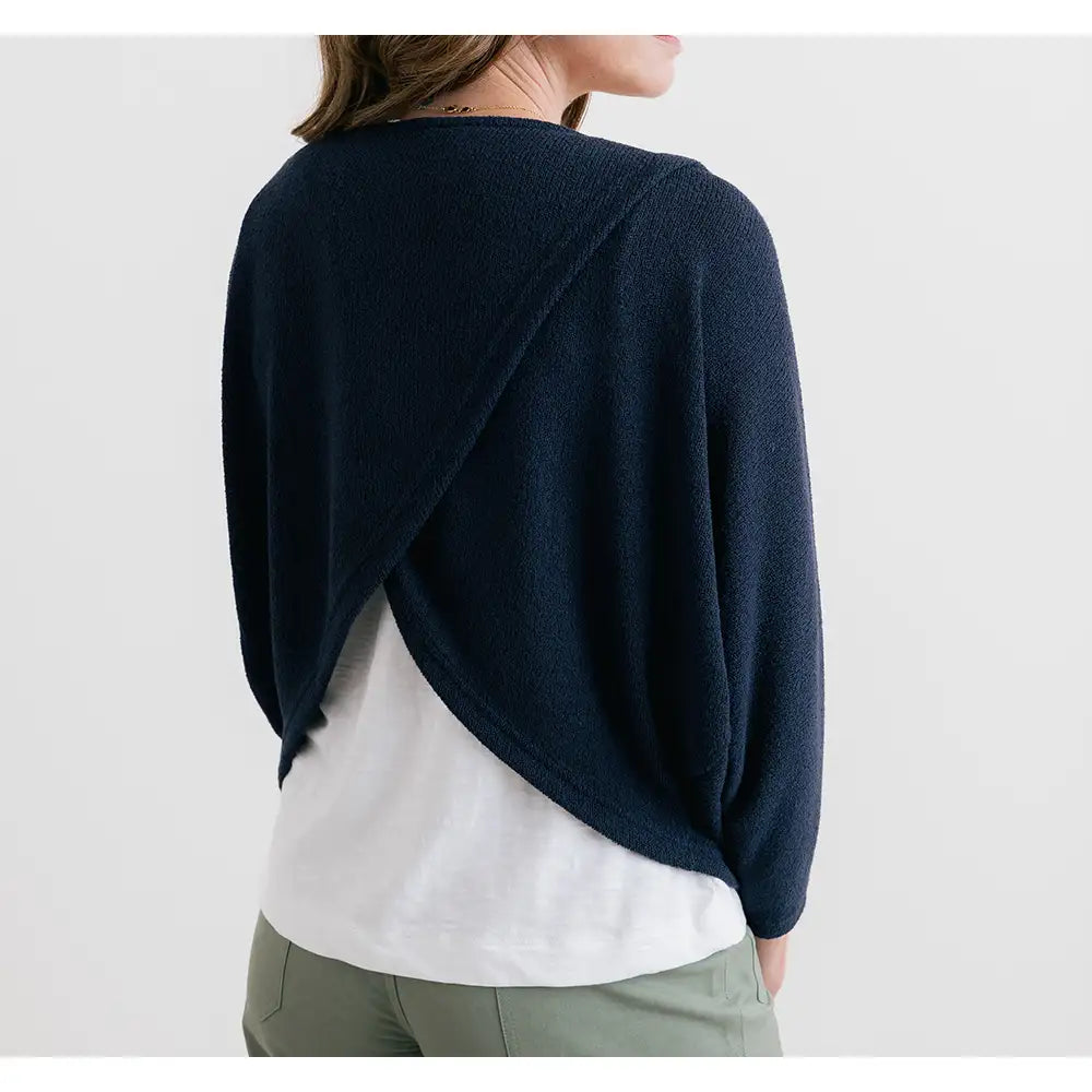 Person wearing a navy blue jumper over a white shirt on a light gray background