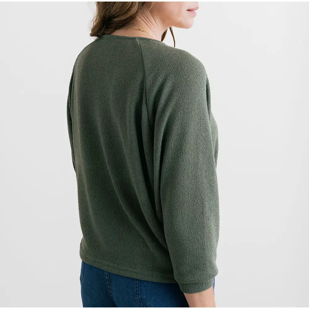 Person wearing a green sweater on a plain background