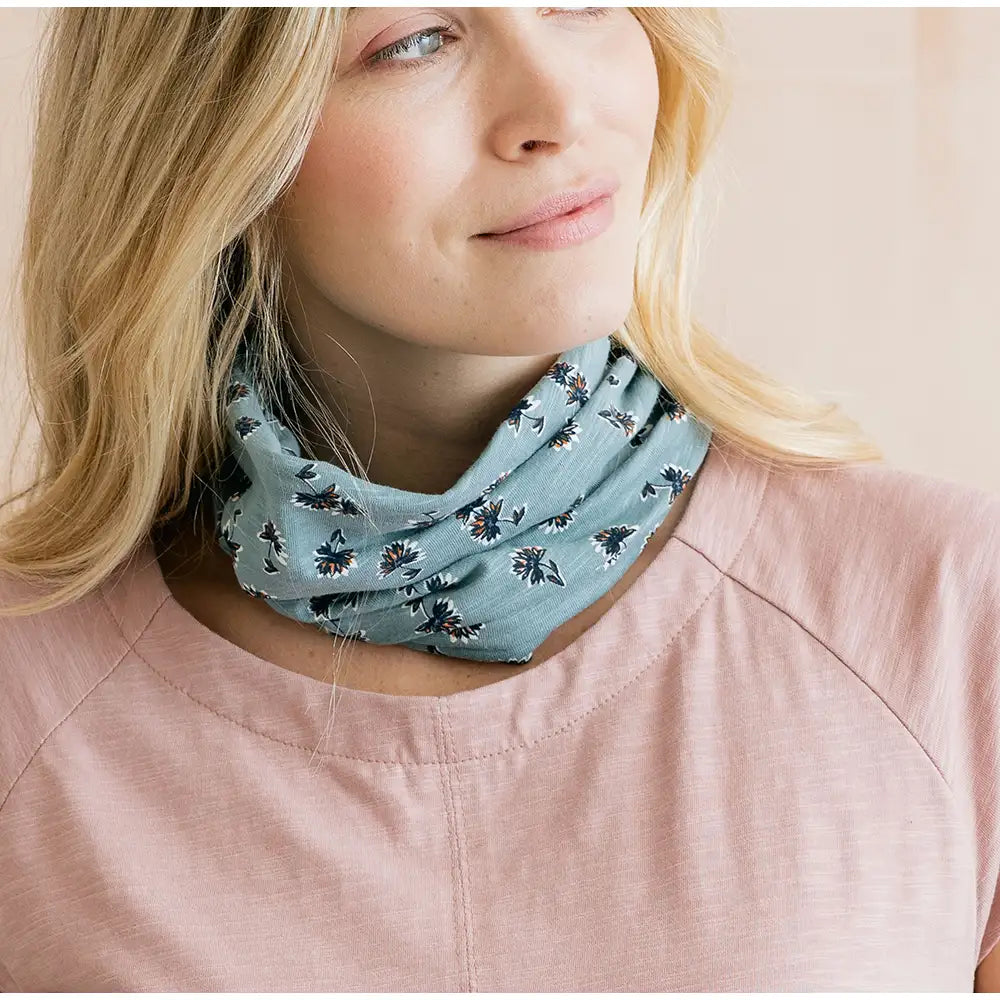 Woman wearing a light blue floral patterned scarf on a plain background