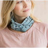 Woman wearing a light blue floral patterned scarf on a plain background