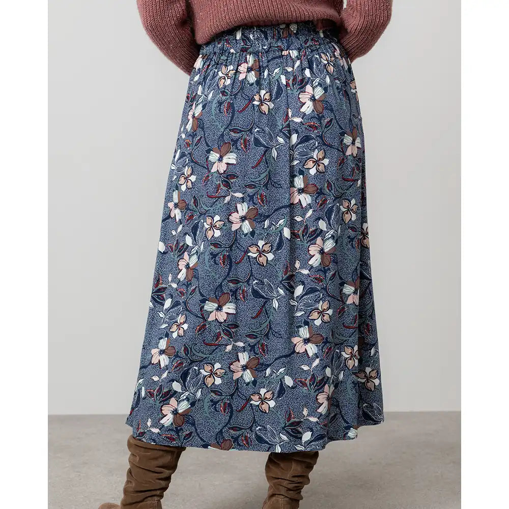 Woman wearing a brown cardigan and floral skirt.