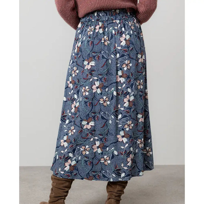Woman wearing a brown cardigan and floral skirt.