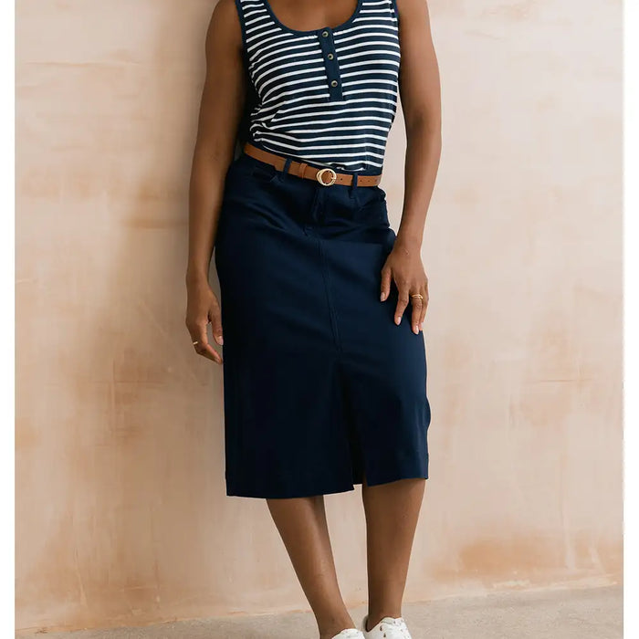 Person wearing a striped top and navy skirt against a beige wall