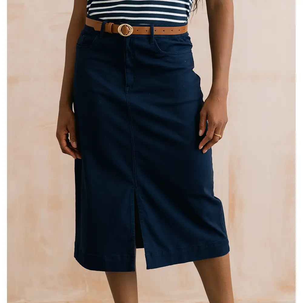 Person wearing a navy skirt with a beige background