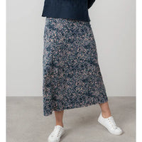 Person wearing a floral skirt and white sneakers on a plain background