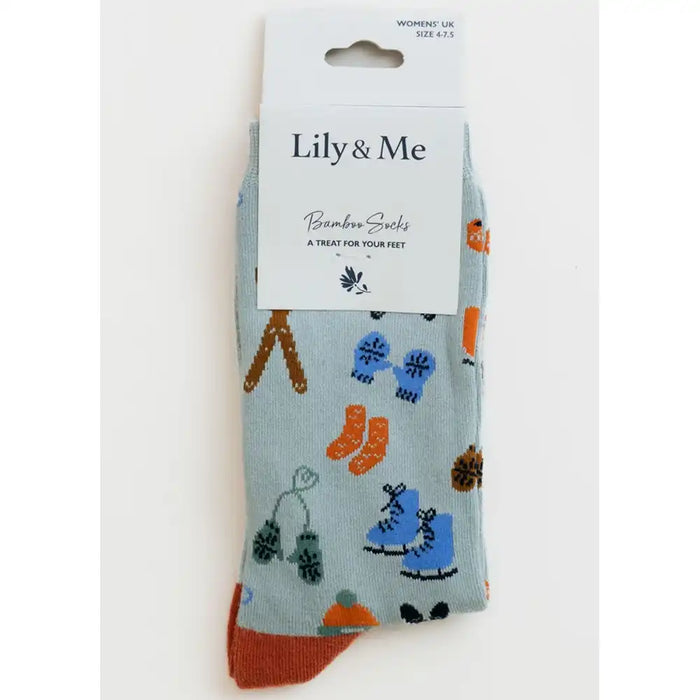 A pair of light blue bamboo socks with a colorful winter boot and snowflake pattern, packaged on a white card labeled 'Lily & Me'.