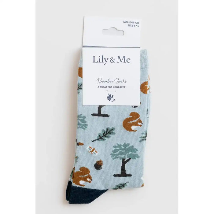 A pair of Lily & Me bamboo socks in a light blue color with a woodland animal print, shown in their original white cardboard packaging against a light gray background.