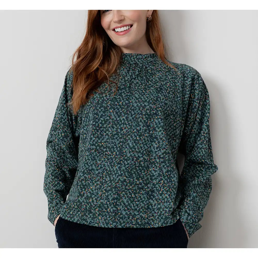 Woman wearing a green floral blouse against a plain background