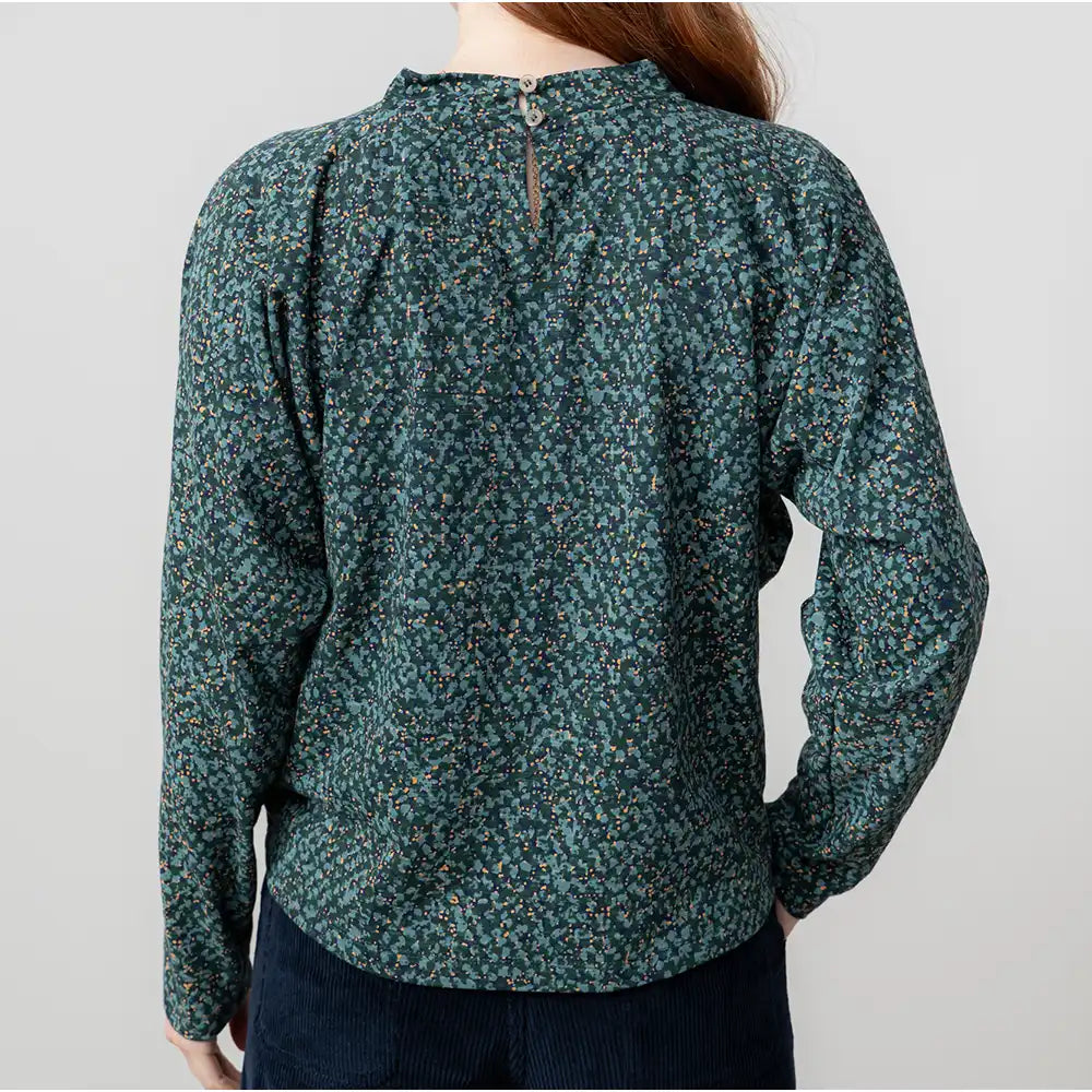 Green floral blouse worn by a person on a plain background