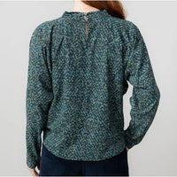 Green floral blouse worn by a person on a plain background