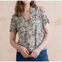 Woman wearing a floral blouse against a beige background
