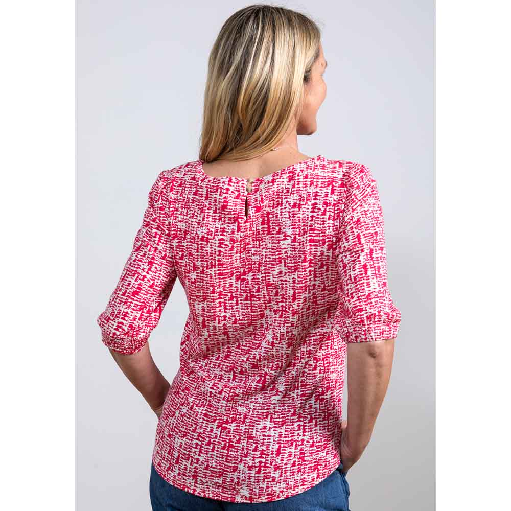 Back of white top with a pink dapple print over, rounded nape of neck with keyhole feature and elbow length sleeve