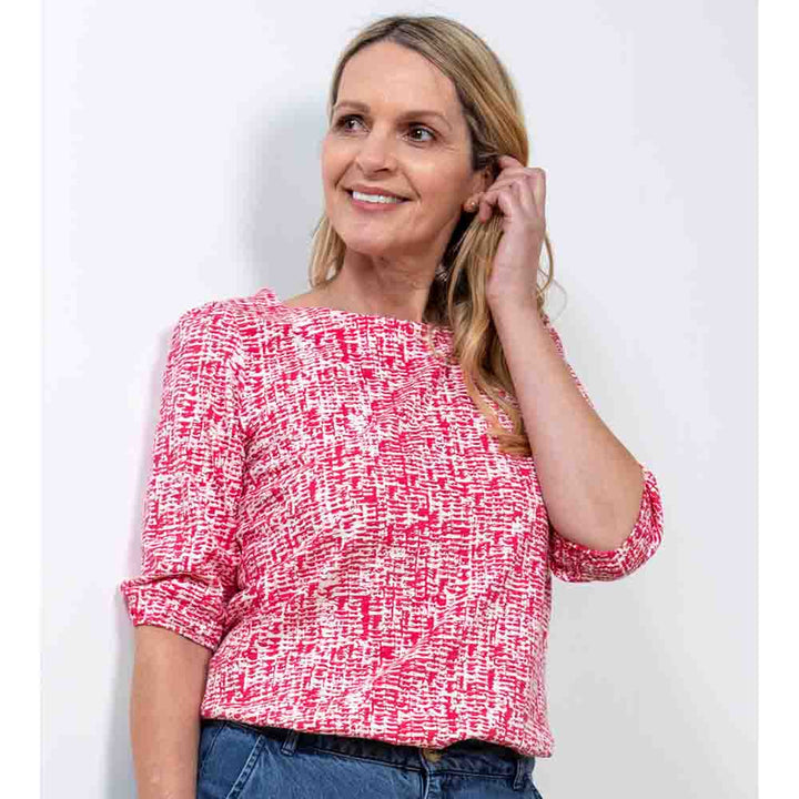 White top with a rounded neckline and elbow length sleeves with a dappled pink print over