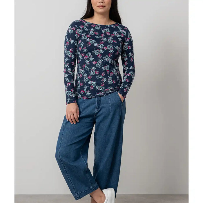 Woman wearing a navy floral top and blue jeans against a plain background