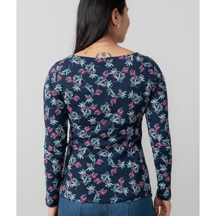 Person wearing a navy blue long-sleeve top with floral pattern on a plain background