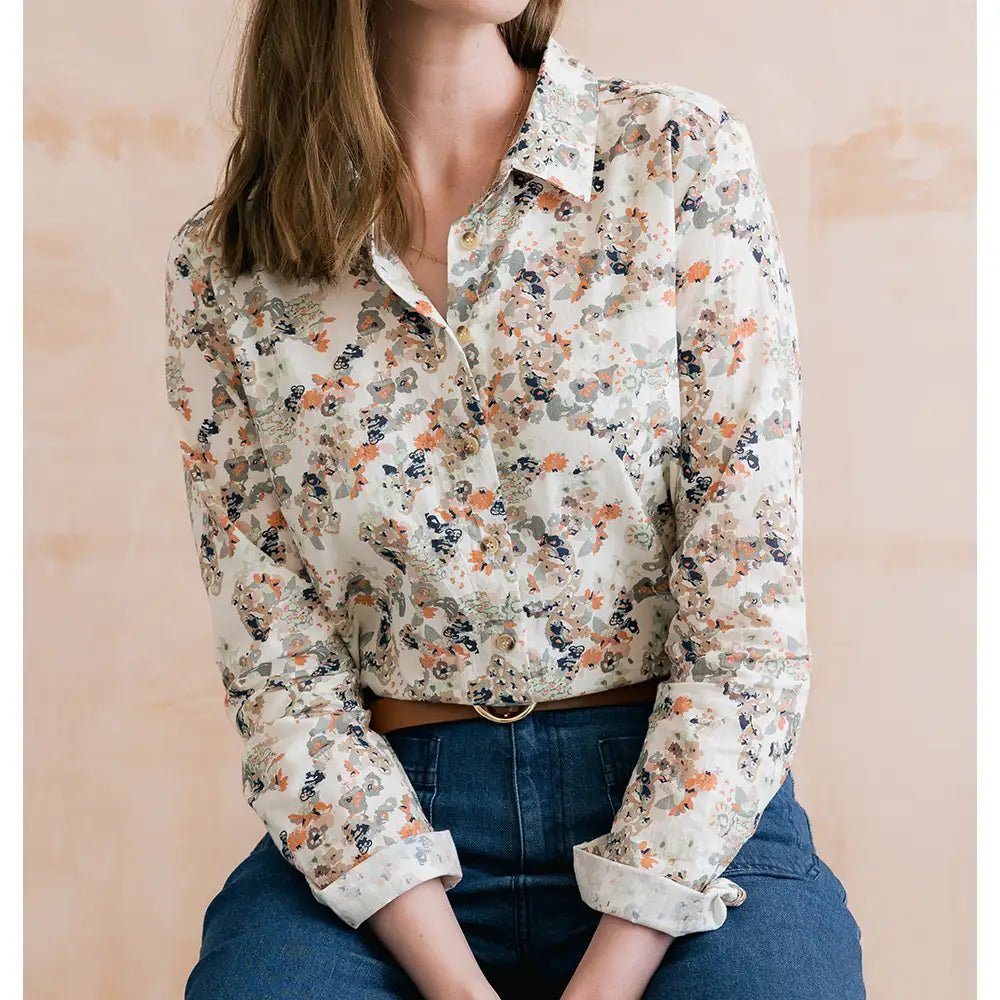 Ecru based shirt with collar and long turned up sleeves. Has a delicate floral pattern on it. 