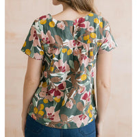 Sage green top with floral design on it in browns, pinks and yellows. Short sleeves and keyhole detail. 