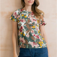 Sage green top with floral design on it in browns, pinks and yellows. Short sleeves and round neckline. 