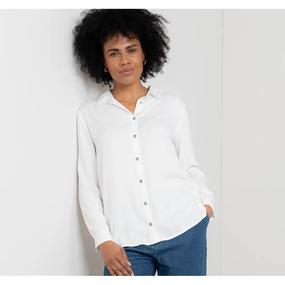 Woman wearing a white shirt and blue jeans against a plain background