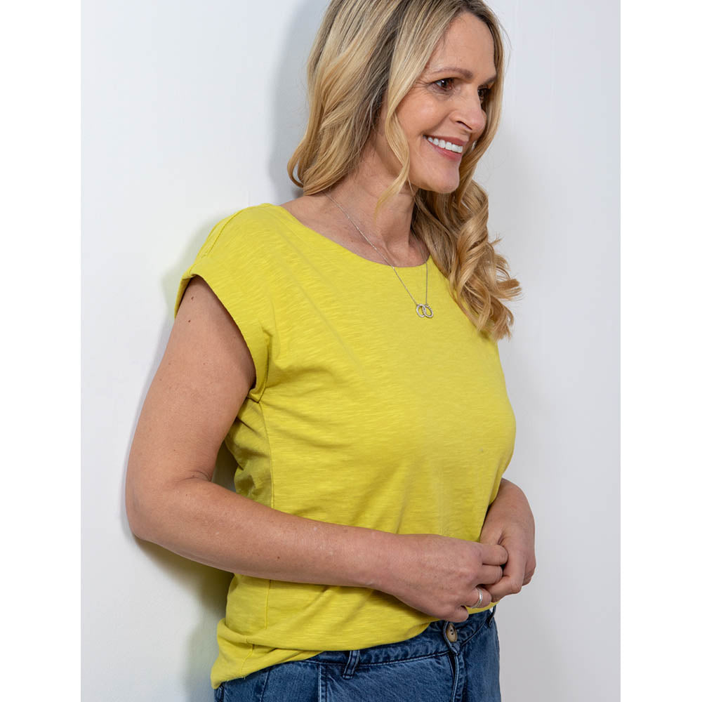 Blonde haired women facing to the side wearing a lime yellow top with a round neck and short sleeve