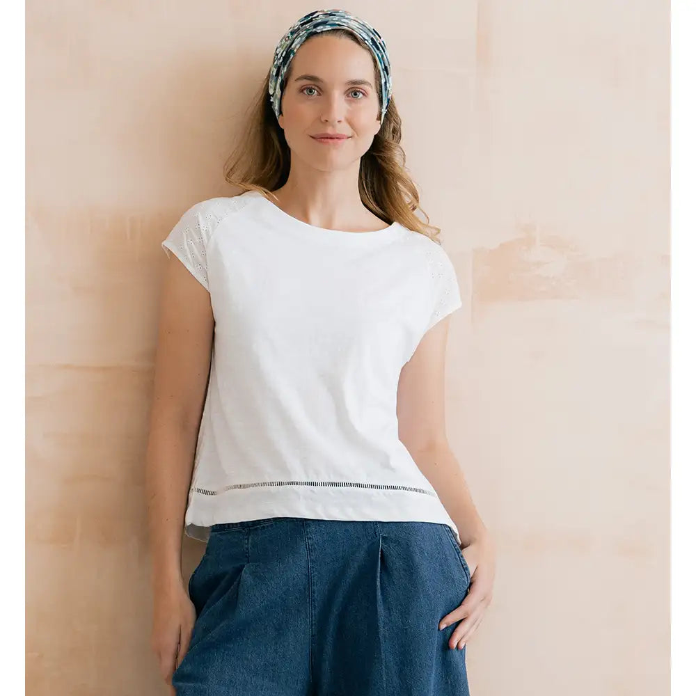 Round neck, short sleeve top in white. Broderie detail just above the hem